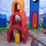 The house shaped piueces from the Gluckskafer castle stacked up on top of each other to create a tower. A Grapat Nin peg doll can be seen standing at the side of the stack. 