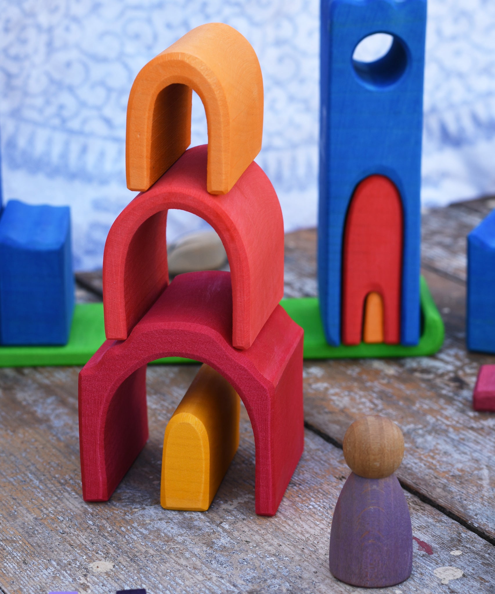 The house shaped piueces from the Gluckskafer castle stacked up on top of each other to create a tower. A Grapat Nin peg doll can be seen standing at the side of the stack. 