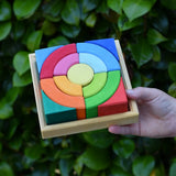 Glückskäfer circles quadrat construction kit in a wooden tray in a child's hand.