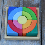 Glückskäfer circles quadrat construction kit in a square display tray placed on a wooden desk. 