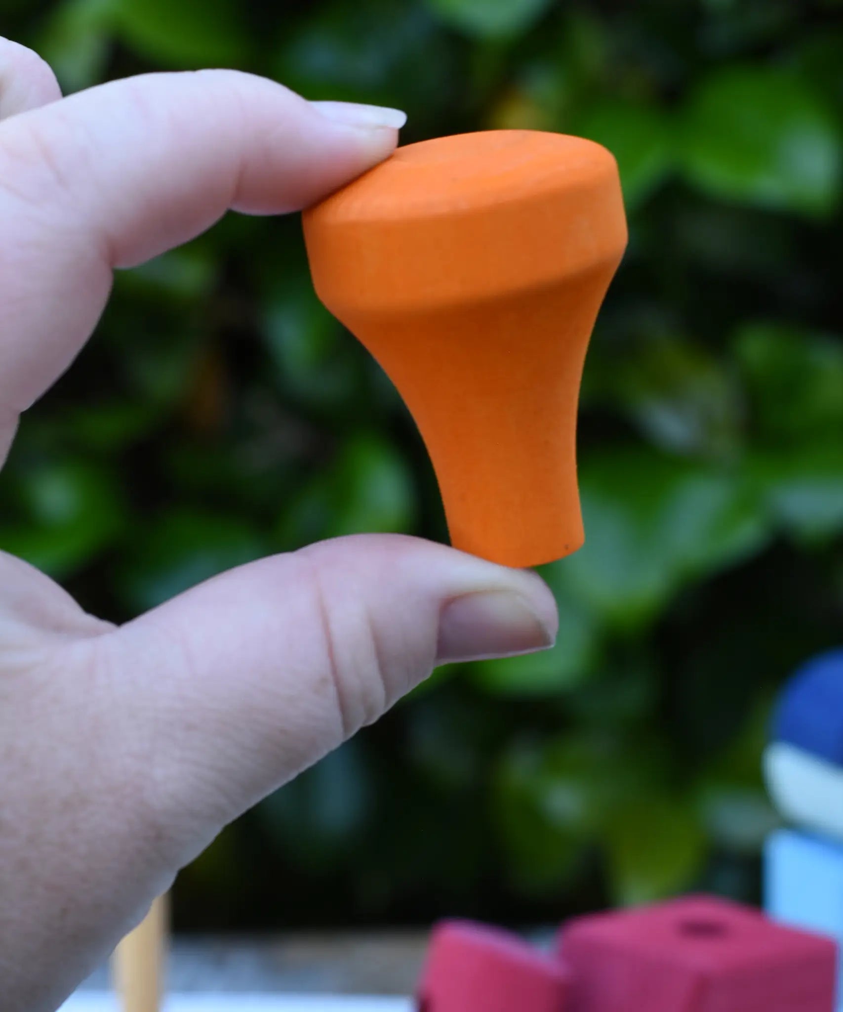 The orange train chimney in an adult's hand from the Glückskäfer colourful shape train wooden toy.