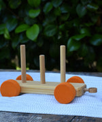One of the base pieces from the Glückskäfer colourful shape train wooden toy placed on a table outdoors.