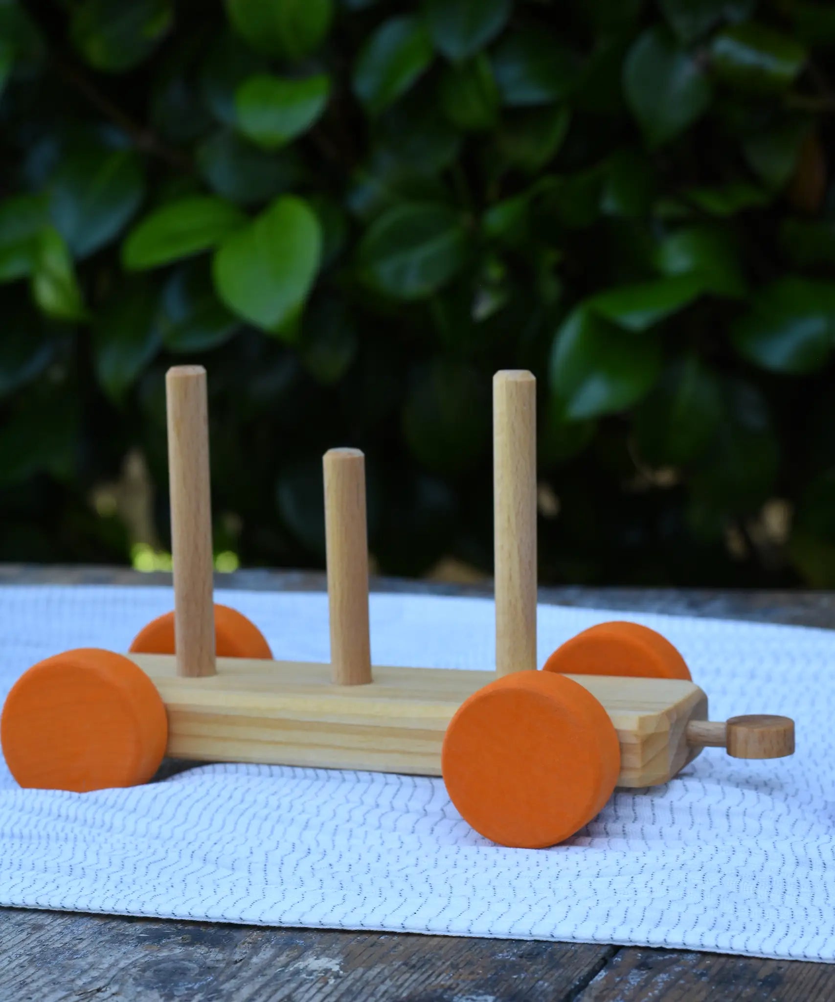 One of the base pieces from the Glückskäfer colourful shape train wooden toy placed on a table outdoors.