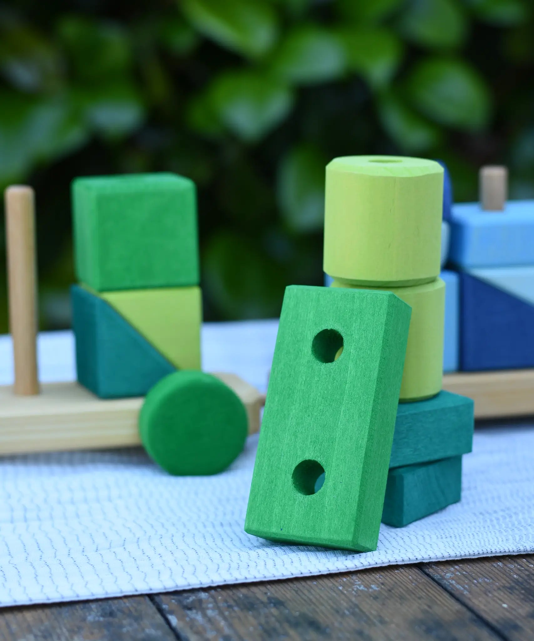 Green blocks from the Glückskäfer colourful shape train wooden toy stacked up on top of each other.