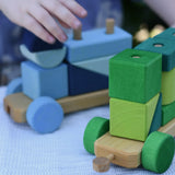 Child playing with the Glückskäfer colourful shape train wooden toy, close up of connectors.