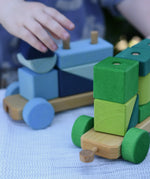Child playing with the Glückskäfer colourful shape train wooden toy, close up of connectors.