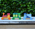 Glückskäfer colourful shape train wooden toy placed on a wooden surface outdoors.