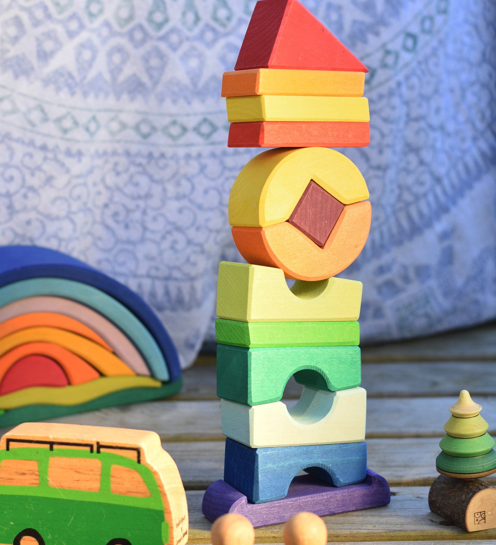 The Glückskäfer Crooked Tower set on a wooden surface surrounded by other wooden toys. 