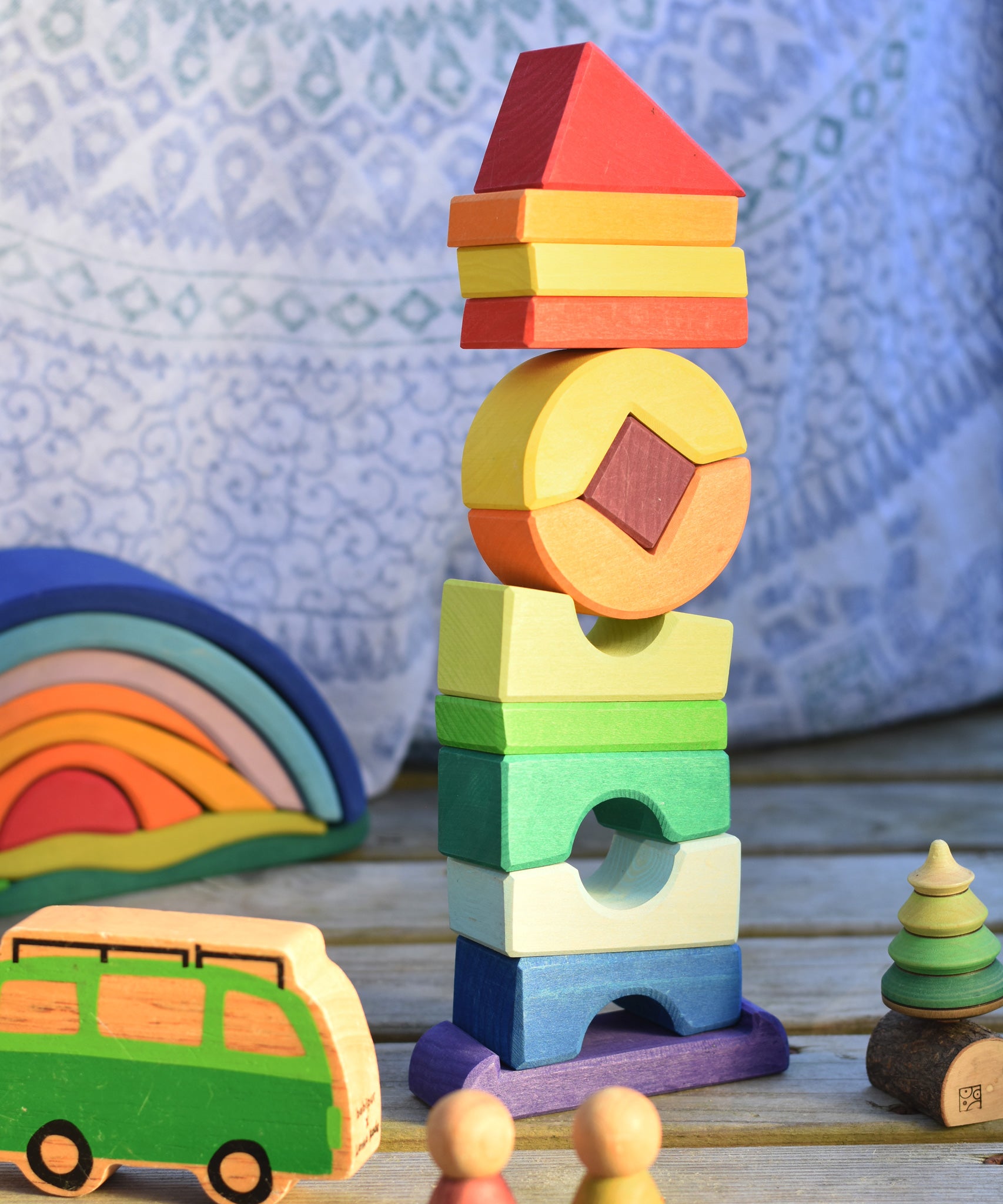 The Glückskäfer Crooked Tower set on a wooden surface surrounded by other wooden toys. 