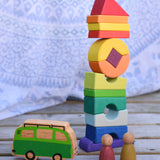 The Glückskäfer Crooked Tower placed on a wooden surface with a Lanka Kade camper van toy and Grapat Nins in front of it. 
