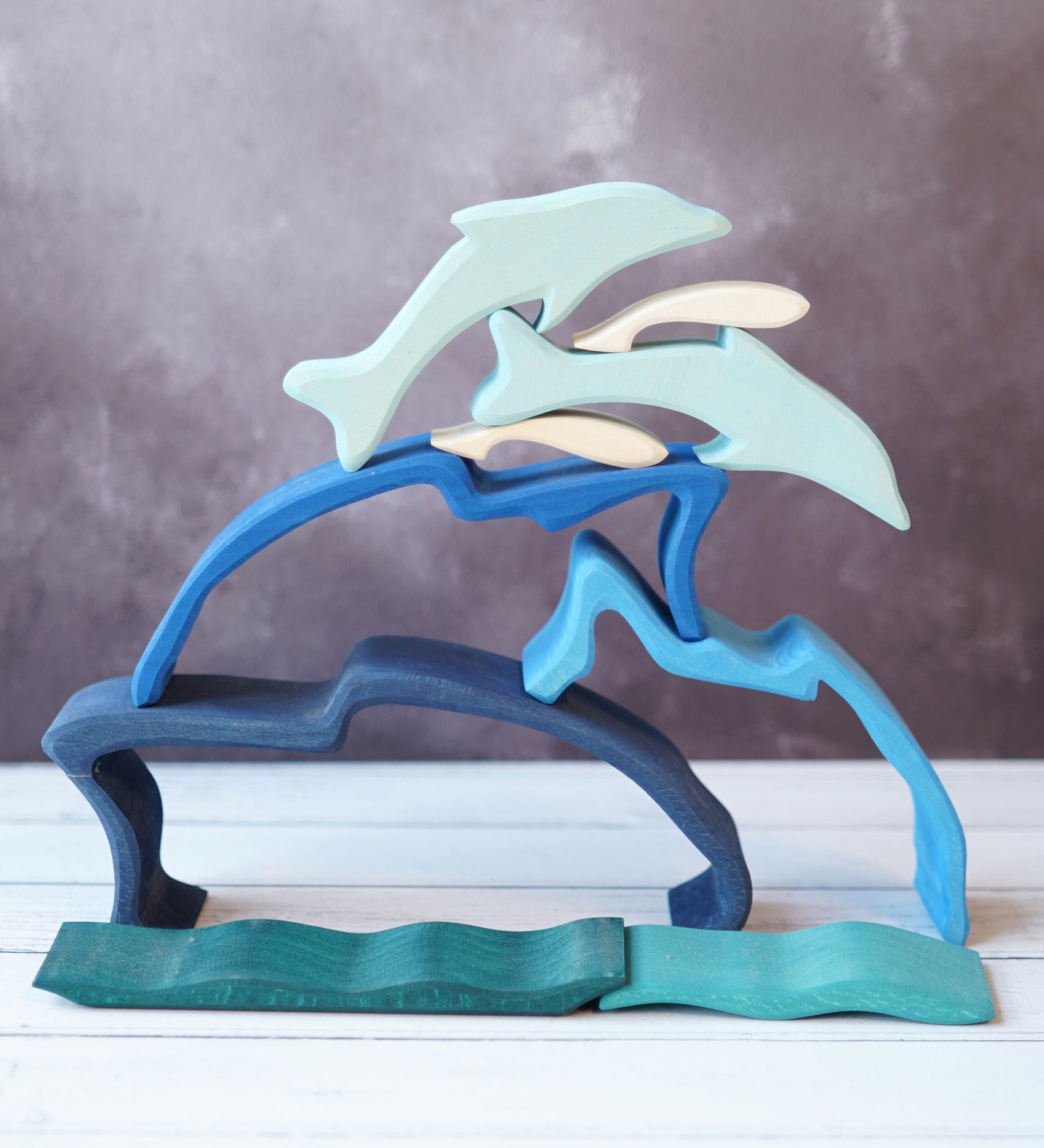 The Gluckskafer Stacking Dolphin taken apart and stacked up on a wooden surface. 