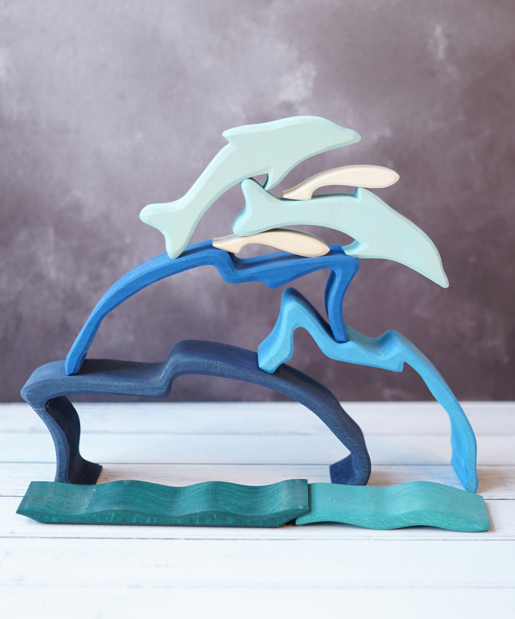 The Gluckskafer Stacking Dolphin taken apart and stacked up on a wooden surface. 