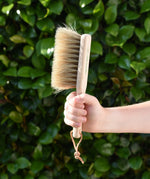 Glückskäfer wooden dust brush with natural horse hair bristles in a child's hand.