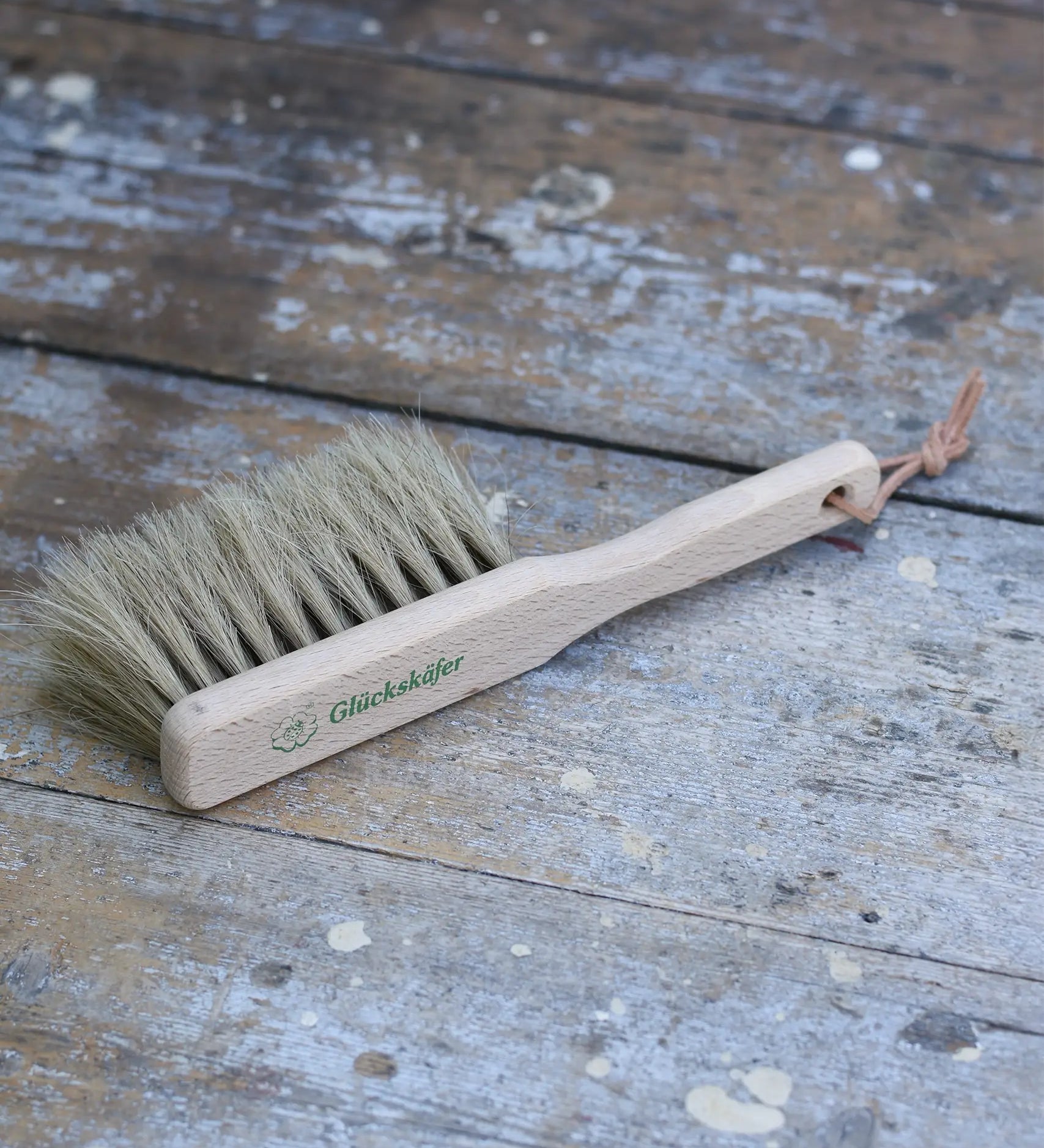 Glückskäfer wooden dust brush with natural horse hair bristles placed on a wooden surface.