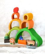 The Glückskäfer Green 8 Piece Arch House shown in a small world play scene set up with other wooden toys including the Bumbu Capybara, Grapat Mis & Match cubes, Lanka Kade Mushroom and Mader tree spinner.