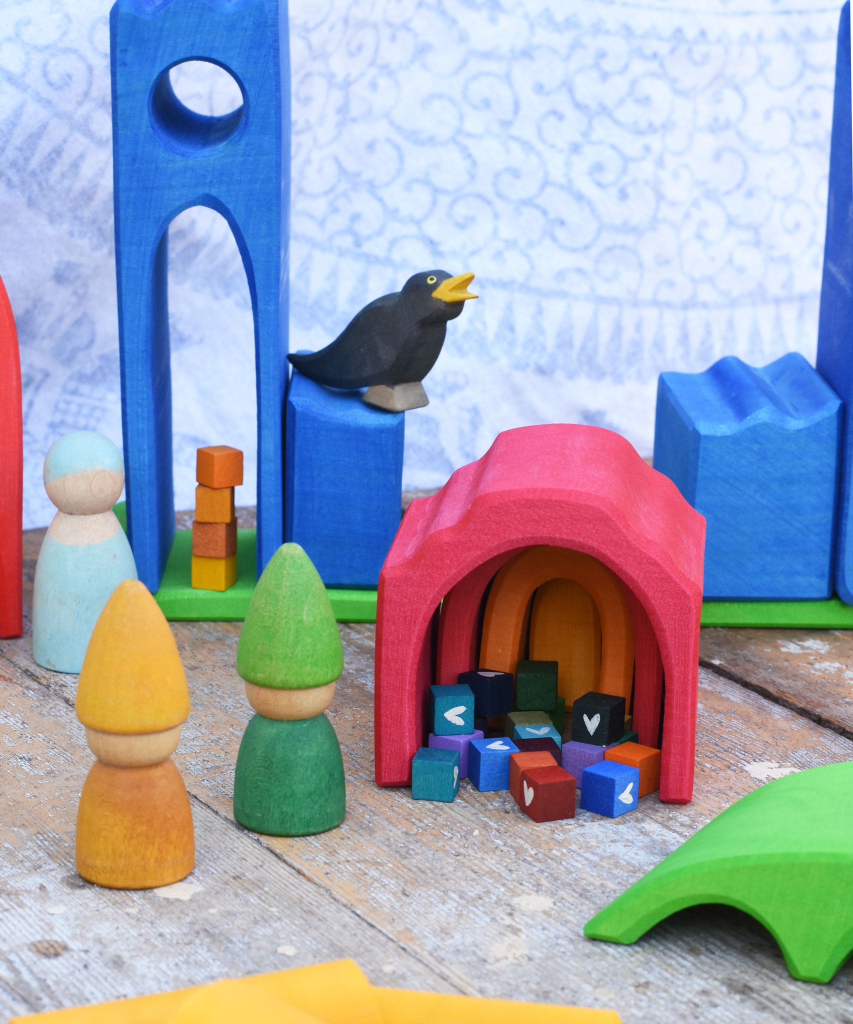 A small world play scene created using the Gluckskafer castle set along with Grapat Tomten wooden peg dolls and other wooden toy figures.