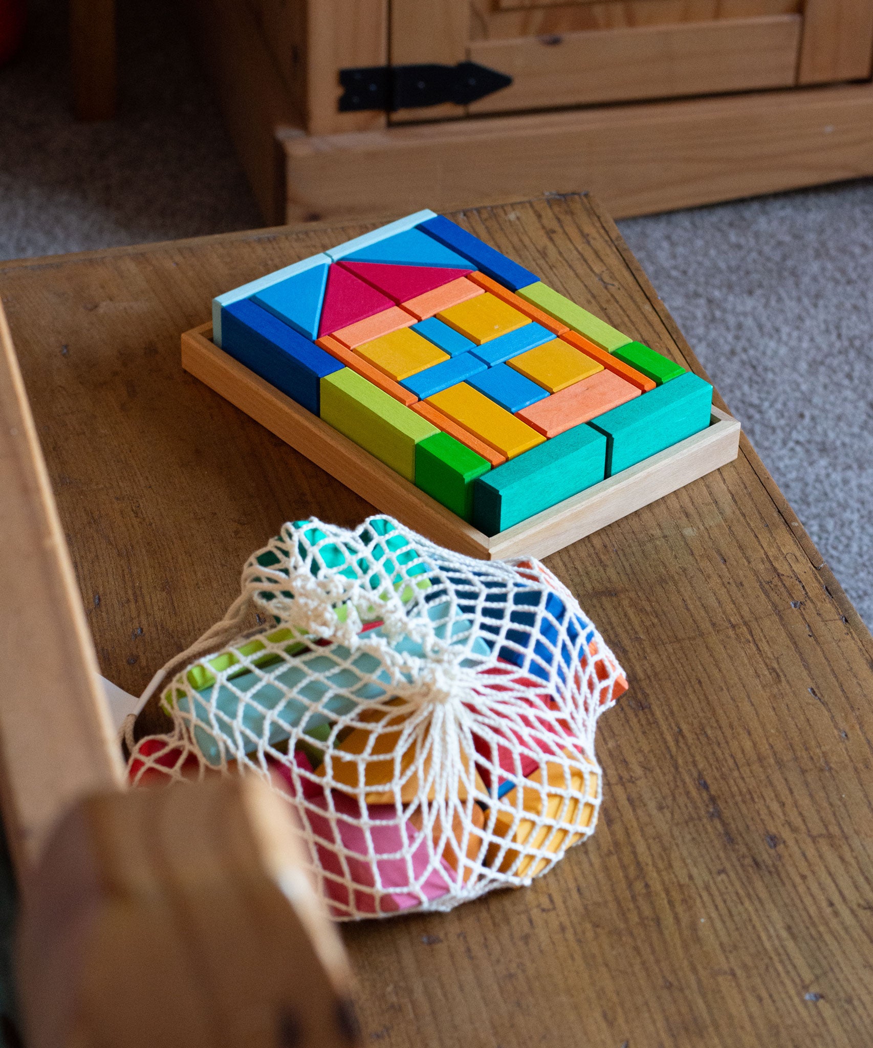 The Glückskäfer house b;locks in a tray set shown next to the 27 Piece Building Blocks Set in their net.