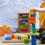 A child stacking blocks from the Glückskäfer 29-Piece House Blocks on top of each other. 