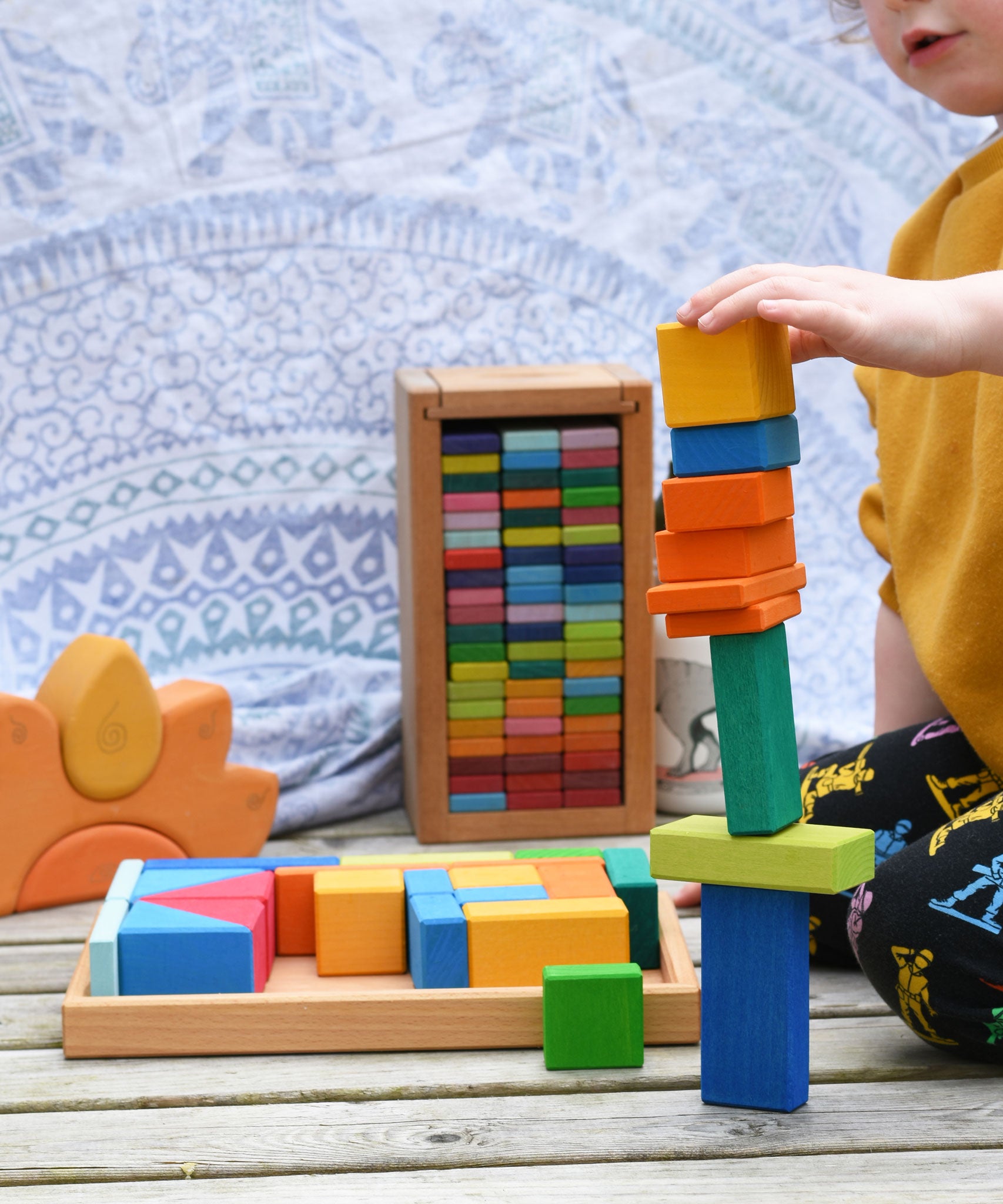 A child stacking blocks from the Glückskäfer 29-Piece House Blocks on top of each other. 