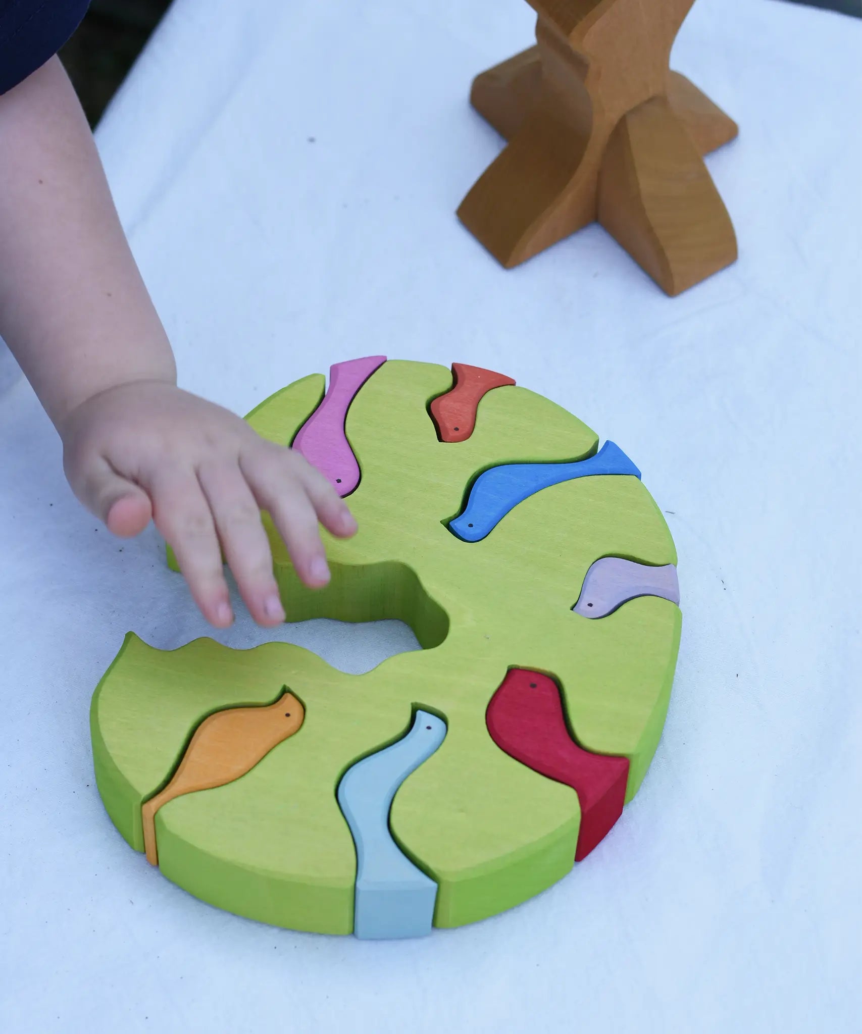 The tree part from the Glückskäfer light green wooden bird tree puzzle stacker toy placed flat on a table.