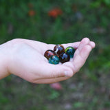 5 glass marbles from the Glückskäfer Marble Track Bridge and Tunnel Set in a child's hand.