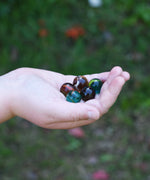 5 glass marbles from the Glückskäfer Marble Track Bridge and Tunnel Set in a child's hand.