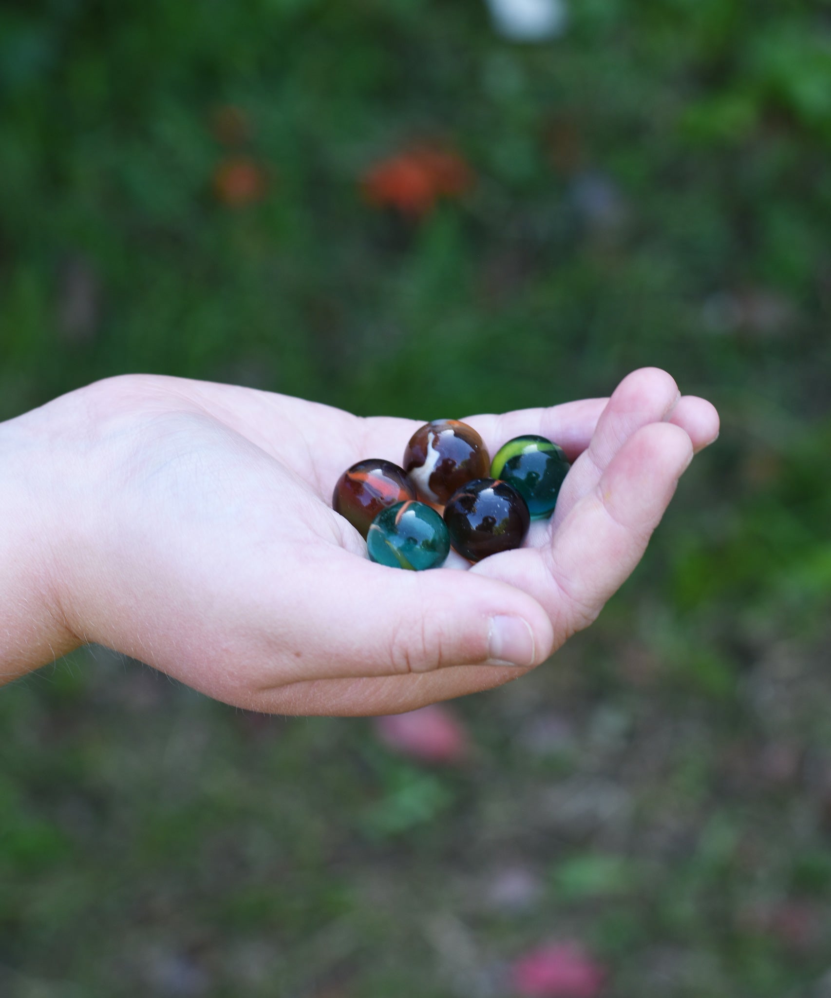 5 glass marbles from the Glückskäfer Marble Track Bridge and Tunnel Set in a child's hand.