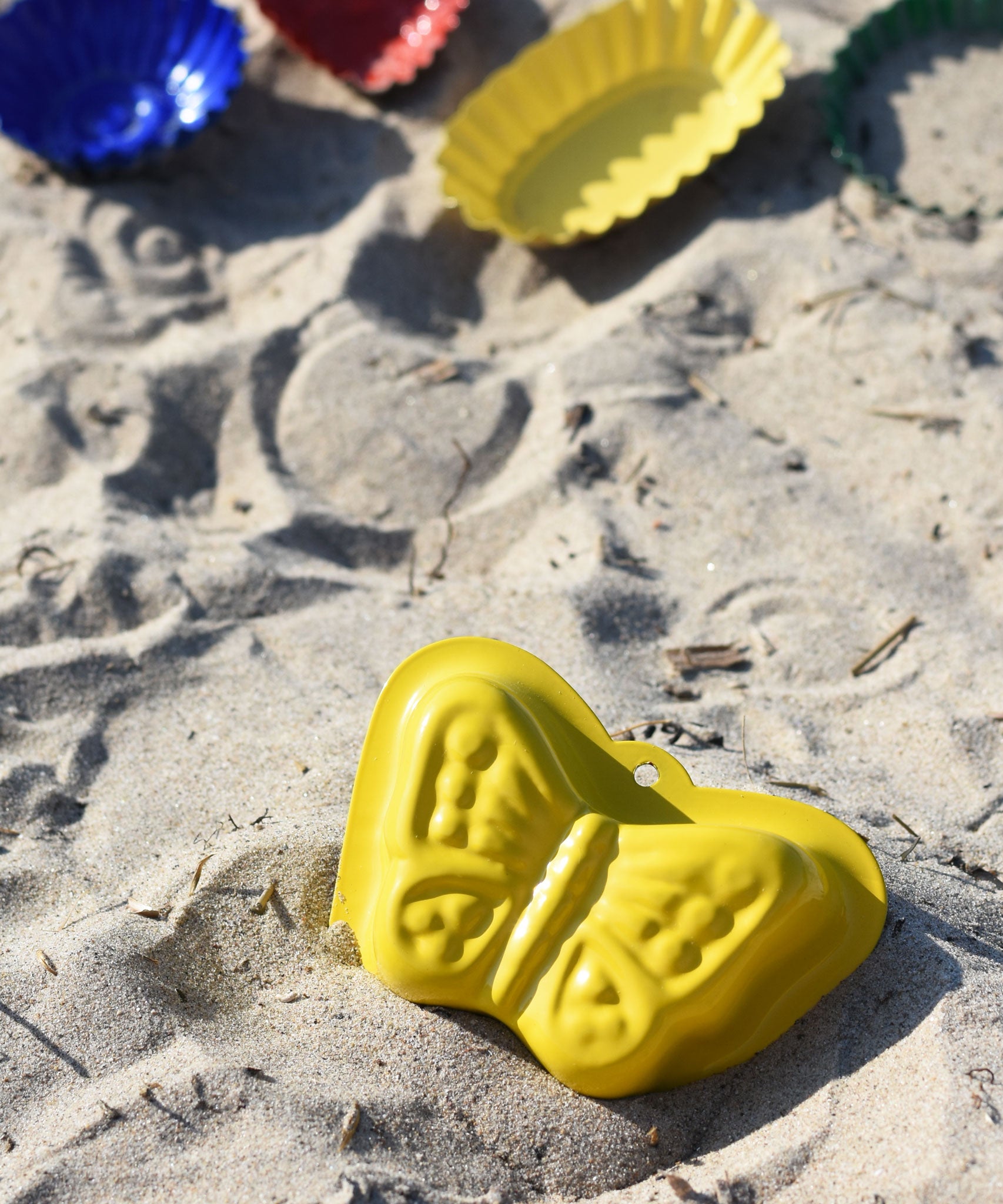 A Glückskäfer Metal butterfly shaped yellow coloured, Sand Mould placed on the sand at a beach. 