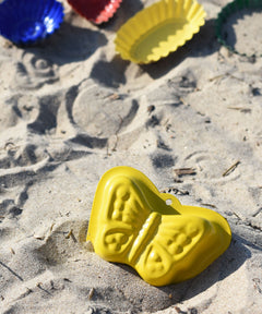 A Glückskäfer Metal butterfly shaped yellow coloured, Sand Mould placed on the sand at a beach. 