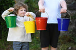 Four Glückskäfer Metal Buckets being held up in a line. There is a green, yellow, red and blue bucket. 