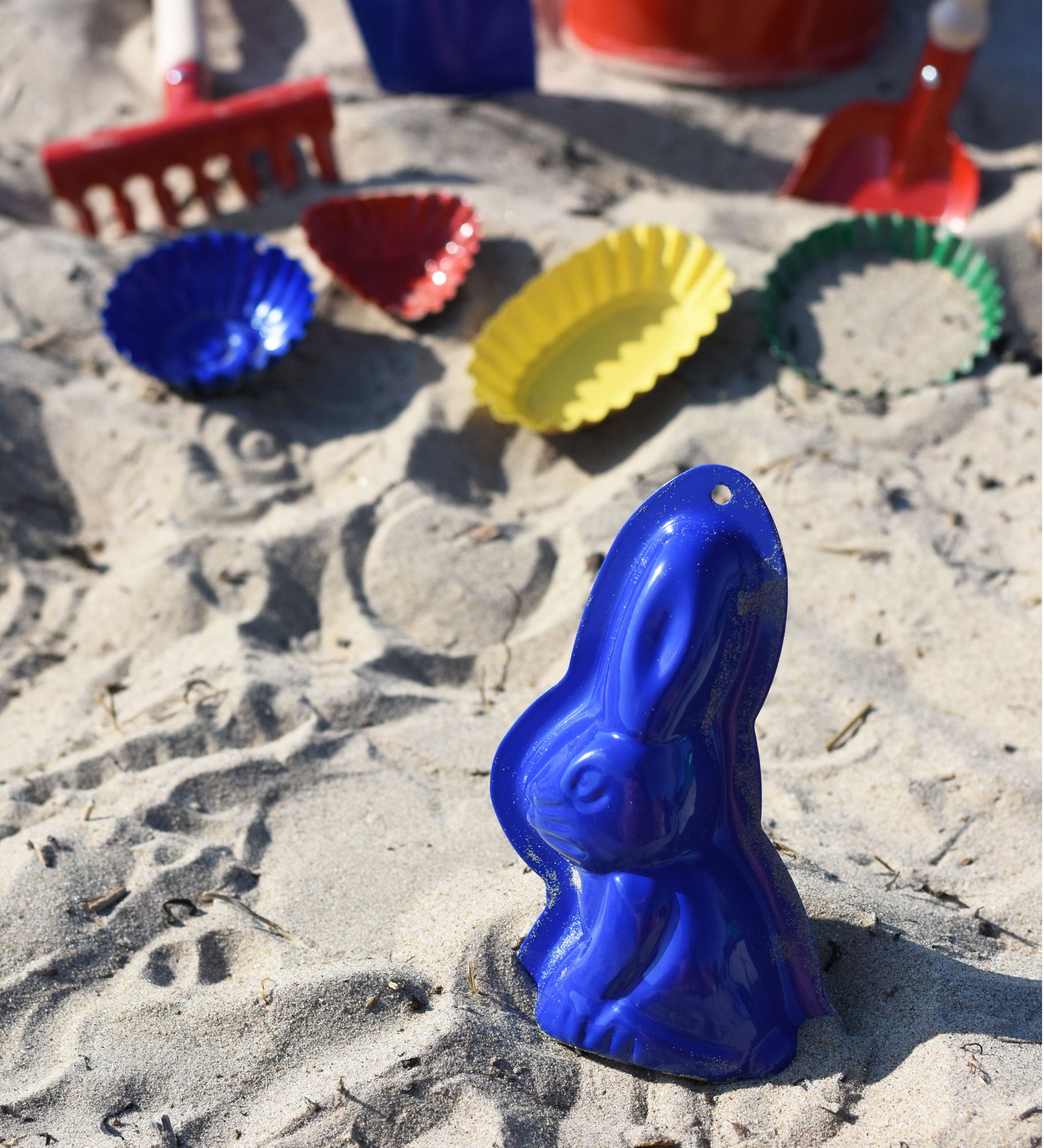 A Glückskäfer Metal Rabbit Sand Mould placed on the sand on a beach