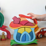 A child playing with the Glückskäfer Mushroom House wooden stacking toy. 