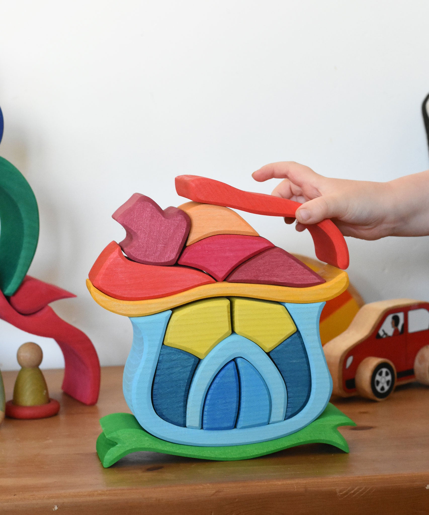 A child playing with the Glückskäfer Mushroom House wooden stacking toy. 
