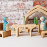 Two wooden peg dolls placed on teh seat pieces from the Gluckskafer Natural All-In House wooden toy. The other pieces from the set can be seen in the background. 