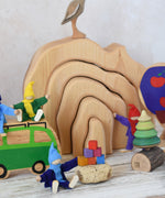 The Glückskäfer Natural Grotto shown in a small world play scene with ther wooden toys including Lanka Kade Lola campervan, Grapat Mis & Match, Mader tree spinner and Magic Wood felt elves.