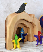 A close up of the Glückskäfer Natural Grotto used as a cave. The Magic Wood elves can be seen standing in the cave with an Ostheimer blackbird sitting on top. 