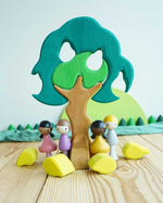 The Glückskäfer Wooden Pear Tree Stacking Puzzle Toy shown in a small world play set up with little wooden dolls. 