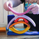 A child creating a stack using pieces from the Glückskäfer wooden Purple Sunset Set Toy.