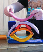A child creating a stack using pieces from the Glückskäfer wooden Purple Sunset Set Toy.