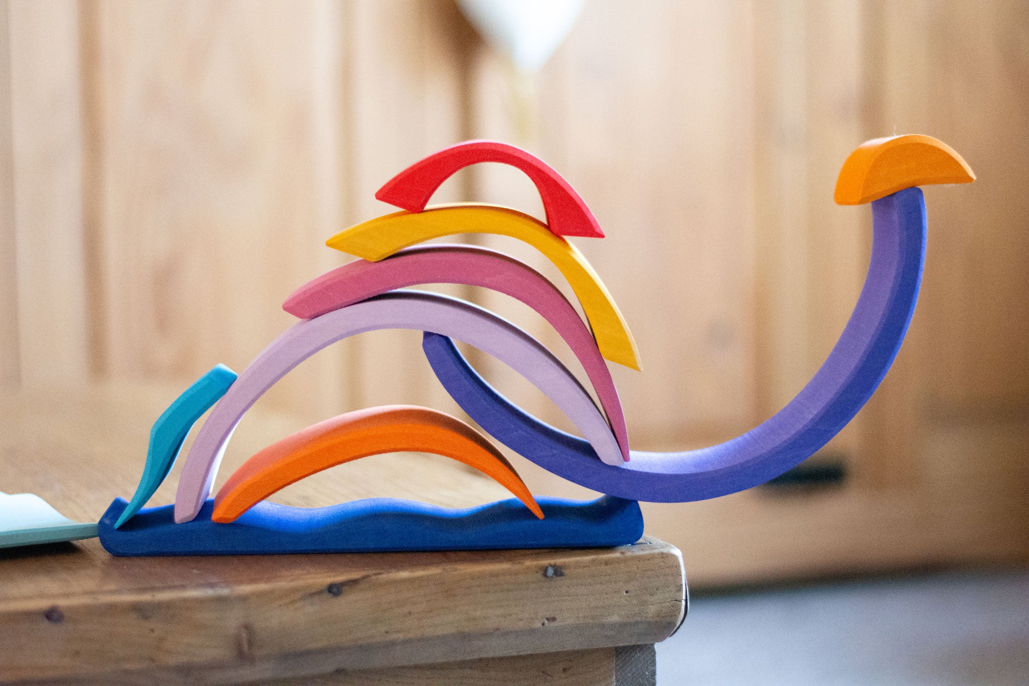 The pieces from the Glückskäfer wooden Purple Sunset Set Toy stacked in the shape of a snail. 