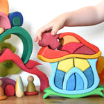 A child playing with the Glückskäfer Mushroom House wooden stacking toy. The are placing the mushroom shaped wooden block back into place. 