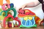 A child playing with the Glückskäfer Mushroom House wooden stacking toy. The are placing the mushroom shaped wooden block back into place. 