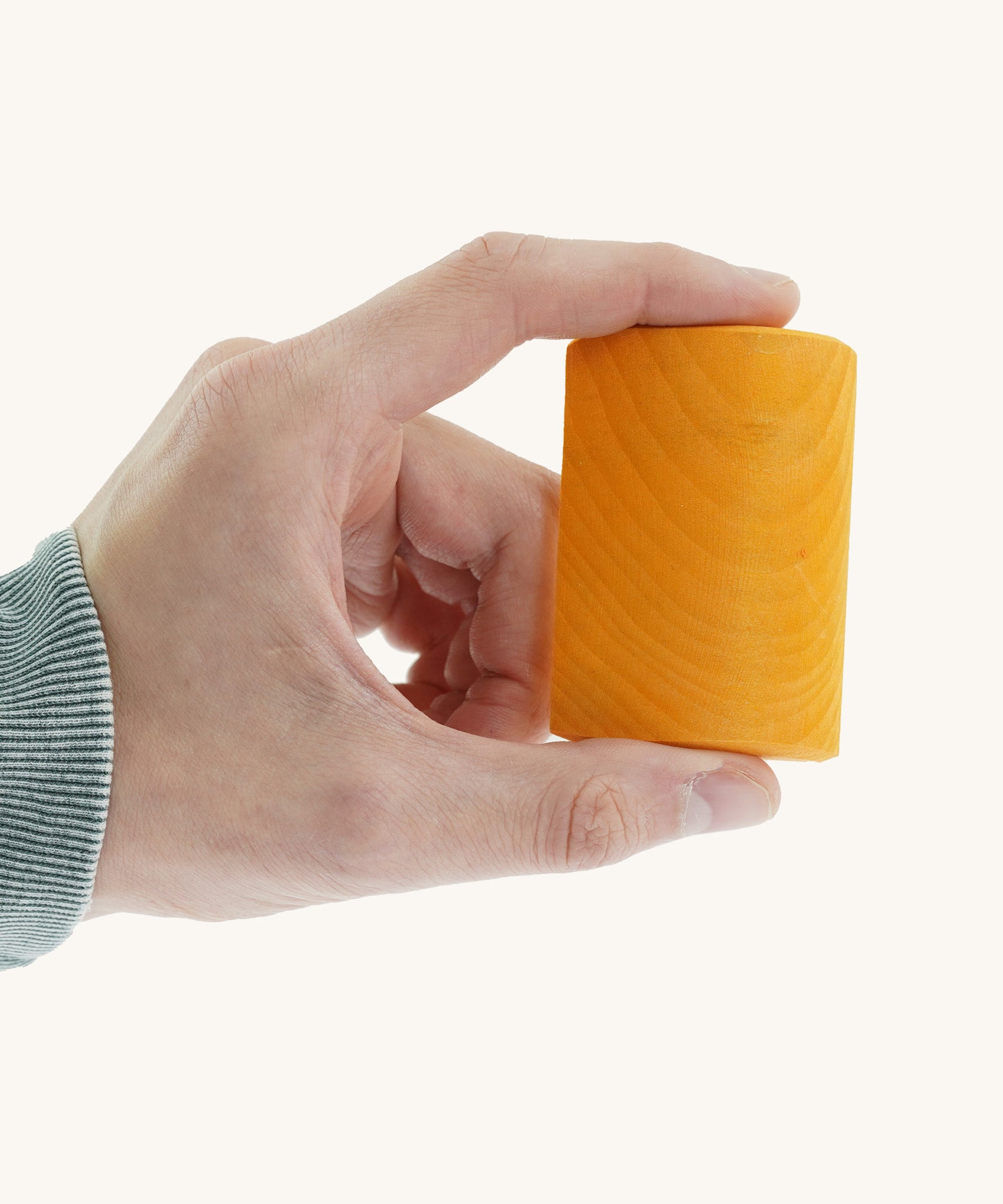 A close up of the small orange block from the Gluckskafer rainbow bridge stacker held by an adult hand showing the scale of the block