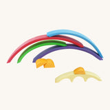 A Gluckskafer rainbow bridge  toy with all of the pieces stacked on top of each other with a orange block sitting on top of the smallest yellow arch piece.