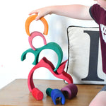 A child stacking the pieces from the Glückskäfer Gable House wooden toy set on top of each other. 