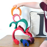 A child stacking the pieces from the Glückskäfer Gable House wooden toy set on top of each other. 