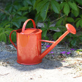 Glückskäfer Red 1L Metal Watering Can placed on concrete floor in a garden.
