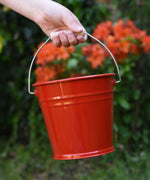 A close up of the Glückskäfer Red Metal Bucket in a child's hand.