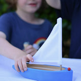 Child playing with the Glückskäfer wooden sailing ship in blue.