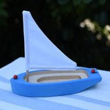 Glückskäfer wooden sailing ship in blue placed on a table outdoors.